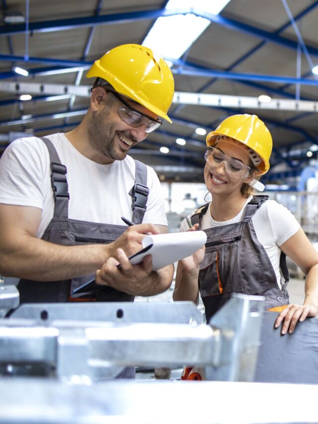Factory workers checking quality of products in large industrial hall.